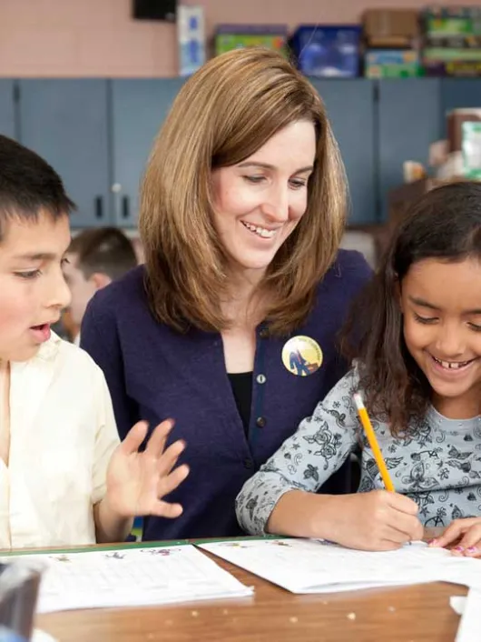 Volunteer working with two students